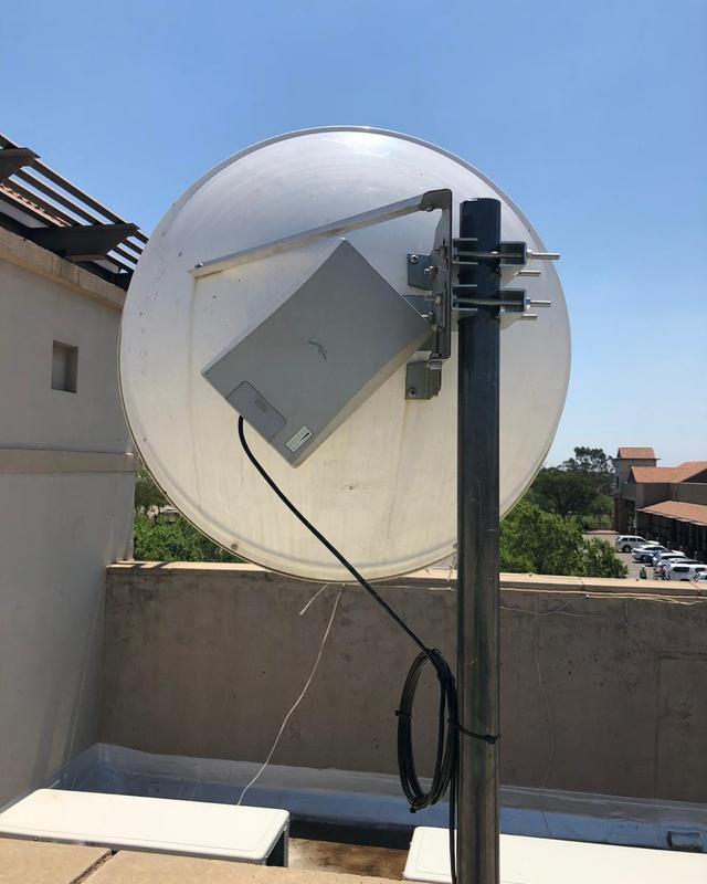 A point-to-point wireless dish mounted on a rooftop pole